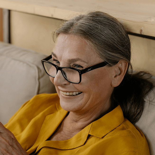 Close-up, circular photo of an older woman with a broad, genuine smile, wearing glasses, and looking towards the upper right. Close-up, circular photo of an older woman with a broad, genuine smile, wearing glasses, and looking towards the upper right.